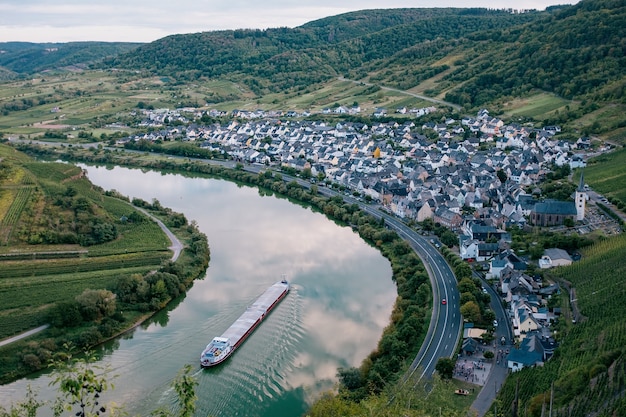 Vue aerienne d un village blotti dans une boucle de riviere entouree de coteaux boises